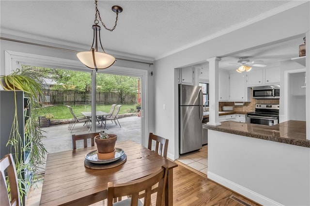 dining area with crown molding, a ceiling fan, light wood-style flooring, baseboards, and a textured ceiling