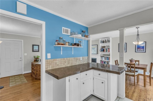 kitchen featuring white cabinetry, open shelves, light wood-style flooring, visible vents, and ornamental molding