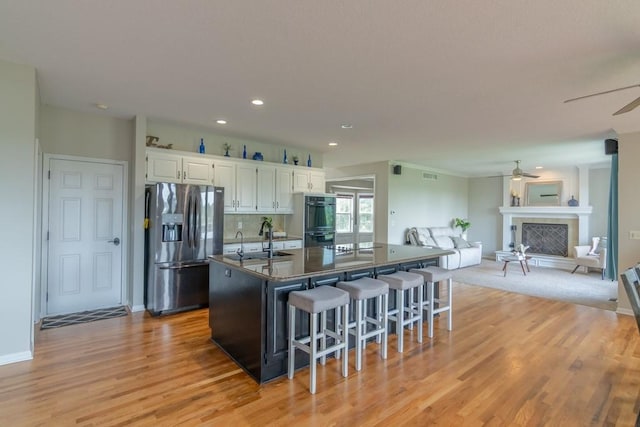 14108 Pine Valley Ct, Basehor, KS 66007 - kitchen with stainless steel refrigerator with ice dispenser, a ceiling fan, a kitchen breakfast bar, a center island with sink, and white cabinets