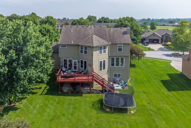 14108 Pine Valley Ct, Basehor, KS 66007 - rear view of house with a deck, a lawn, and a trampoline