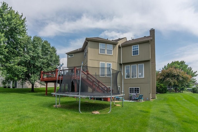 14108 Pine Valley Ct, Basehor, KS 66007 - rear view of house with stairs, a trampoline, a wooden deck, and a yard