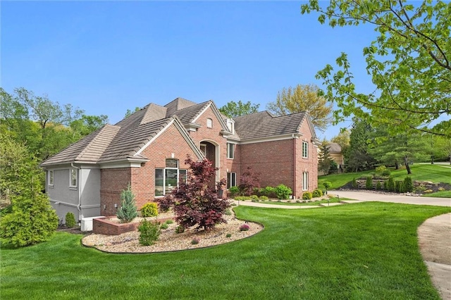 view of front of house with brick siding, a front lawn, and a tiled roof