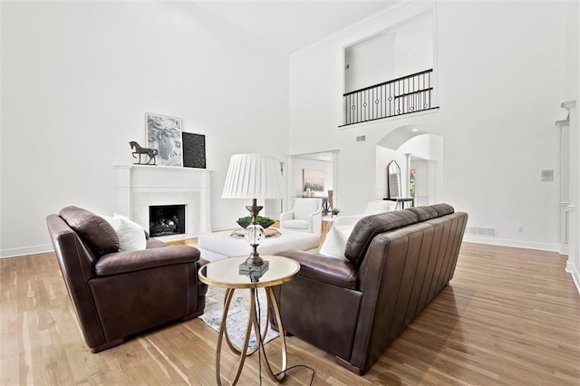 living area with light wood-style floors, arched walkways, baseboards, and visible vents
