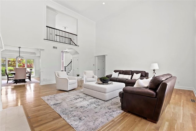 living room featuring light wood-style floors, arched walkways, stairway, and visible vents