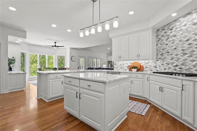 kitchen featuring gas cooktop, a center island, recessed lighting, decorative backsplash, and wood finished floors