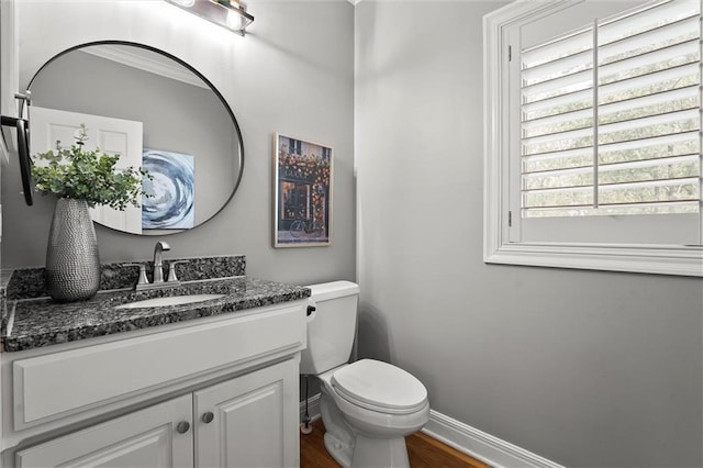 bathroom featuring toilet, baseboards, wood finished floors, and vanity