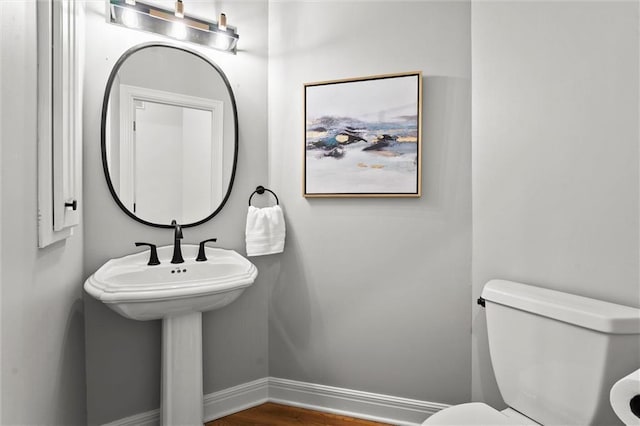 half bathroom featuring toilet, baseboards, and wood finished floors