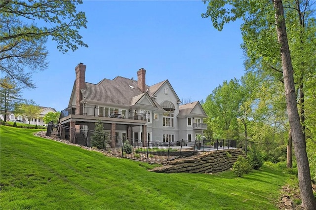 back of property with a lawn, fence, and a balcony