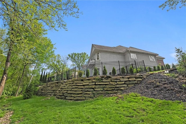 view of property exterior with a lawn, stucco siding, and fence
