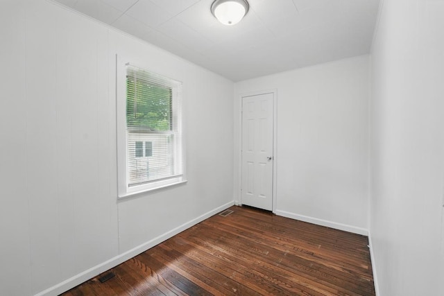 unfurnished room featuring dark wood-type flooring and baseboards