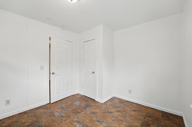 spare room featuring stone finish flooring and baseboards