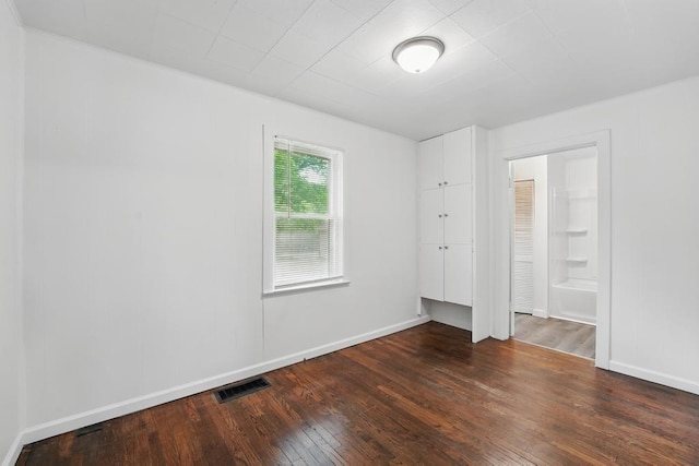 unfurnished bedroom with dark wood finished floors, connected bathroom, and baseboards