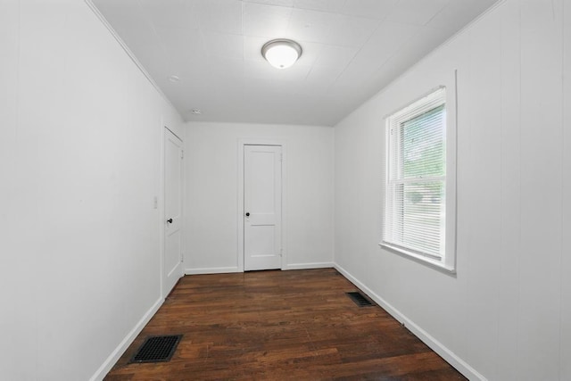 spare room featuring dark wood-style floors, ornamental molding, and baseboards