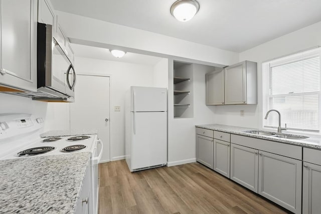 kitchen featuring white appliances, a sink, gray cabinets, and light wood-type flooring