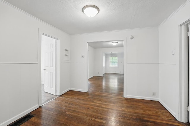 hallway featuring ornamental molding, hardwood / wood-style floors, a textured ceiling, a wainscoted wall, and a decorative wall