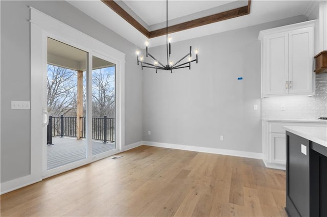 24919 W 145th St, Olathe, KS 66061 - unfurnished dining area with a chandelier, light wood-type flooring, baseboards, and a tray ceiling