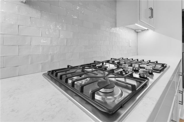 24919 W 145th St, Olathe, KS 66061 - kitchen view of stainless steel gas stovetop, tasteful backsplash, white cabinetry, and light stone countertops