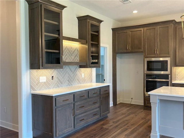 24919 W 145th St, Olathe, KS 66061 - kitchen with stainless steel oven, light countertops, built in microwave, dark wood-style flooring, and tasteful backsplash