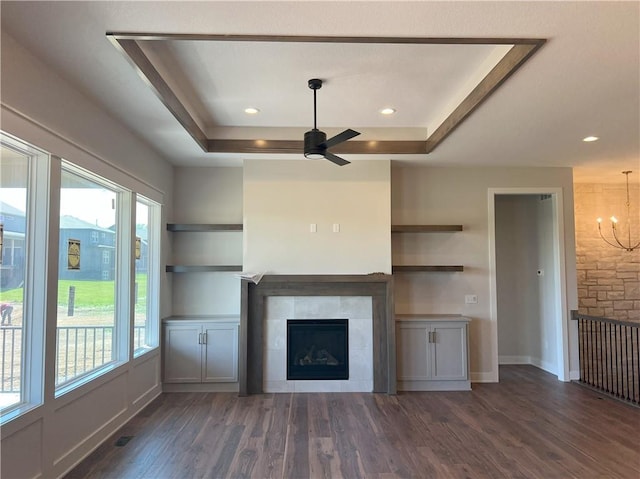 24919 W 145th St, Olathe, KS 66061 - unfurnished living room featuring a tiled fireplace, dark wood-style flooring, a chandelier, ceiling fan, and a raised ceiling