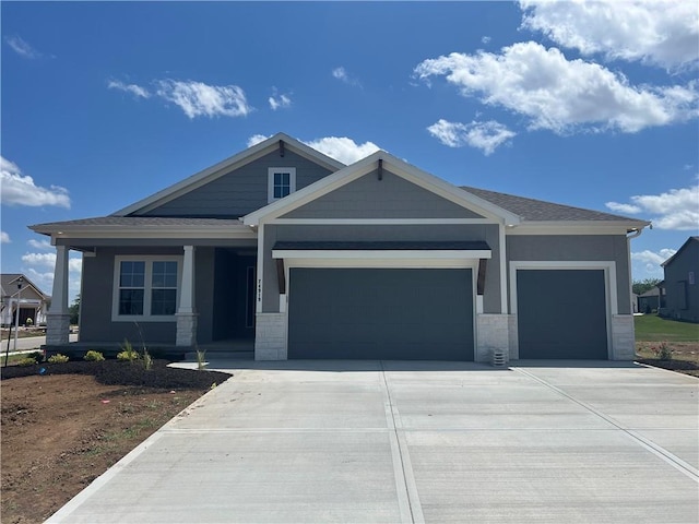 24919 W 145th St, Olathe, KS 66061 - craftsman house featuring a garage, driveway, covered porch, and stone siding