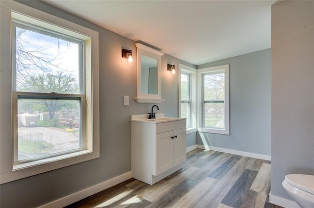 611 E 8th St, Wellsville, KS 66092 - bathroom with baseboards, wood finished floors, toilet, and vanity