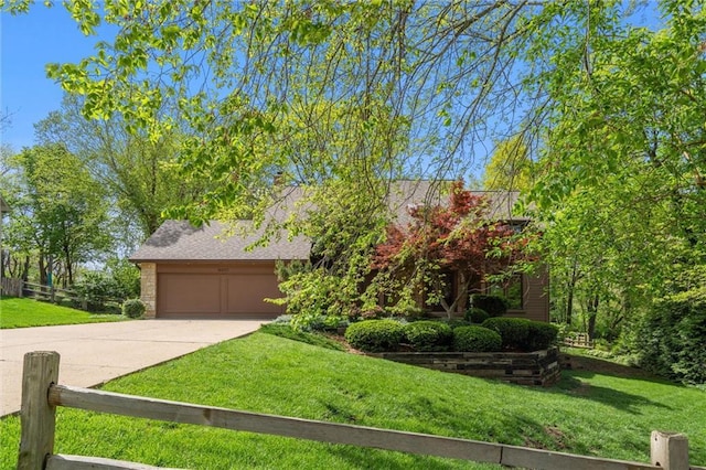 obstructed view of property featuring fence, an attached garage, concrete driveway, and a front lawn