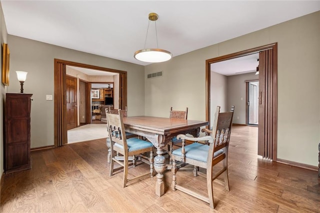 dining area with visible vents, light wood-style floors, and baseboards