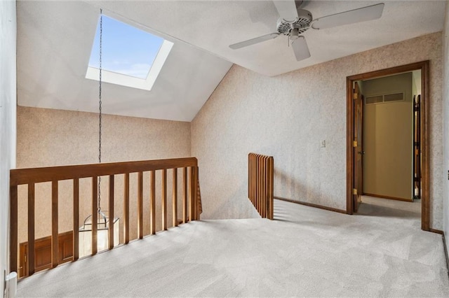 interior space with visible vents, a ceiling fan, carpet, and vaulted ceiling with skylight