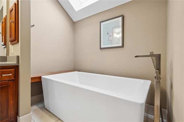 bathroom with a skylight, vanity, tile patterned flooring, and a freestanding bath