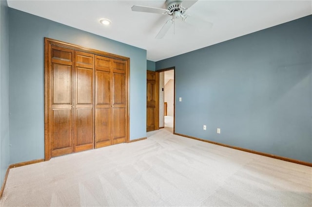 unfurnished bedroom with baseboards, a ceiling fan, a closet, and light carpet