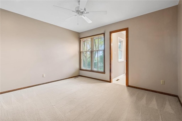 unfurnished room featuring baseboards, a ceiling fan, and light colored carpet