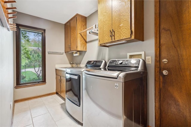 washroom with baseboards, washing machine and clothes dryer, a sink, cabinet space, and light tile patterned floors