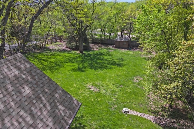 view of yard featuring a fenced backyard, a storage unit, and an outbuilding