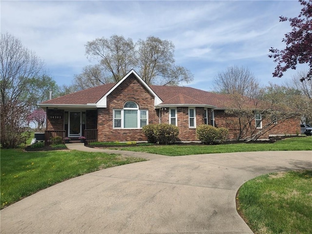 ranch-style home featuring brick siding, a shingled roof, a front lawn, and a porch