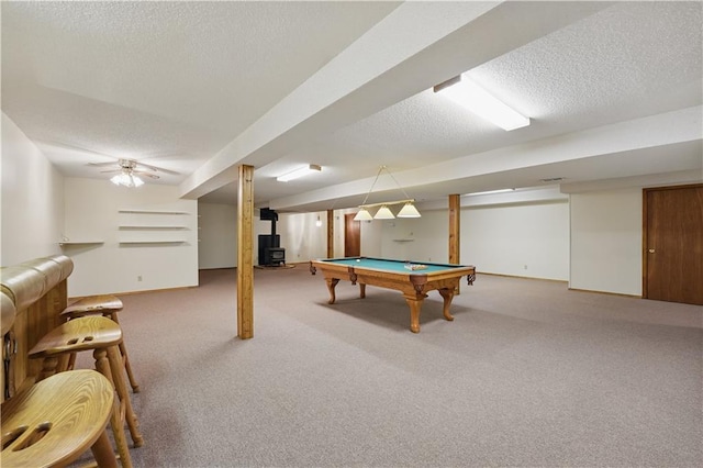 rec room featuring a wood stove, baseboards, a textured ceiling, pool table, and carpet flooring
