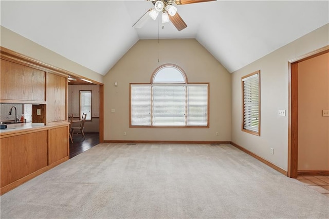 unfurnished living room with a sink, light carpet, a ceiling fan, and vaulted ceiling