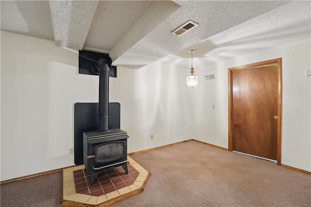 unfurnished living room with visible vents, a wood stove, and a textured ceiling