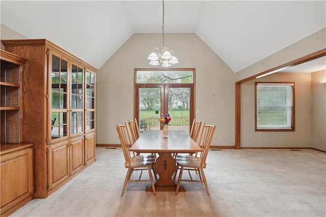 dining space featuring an inviting chandelier, plenty of natural light, lofted ceiling, and light colored carpet