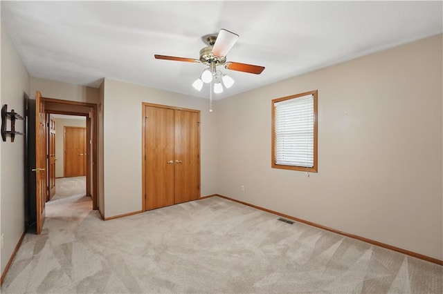 unfurnished bedroom with a closet, baseboards, light colored carpet, and visible vents
