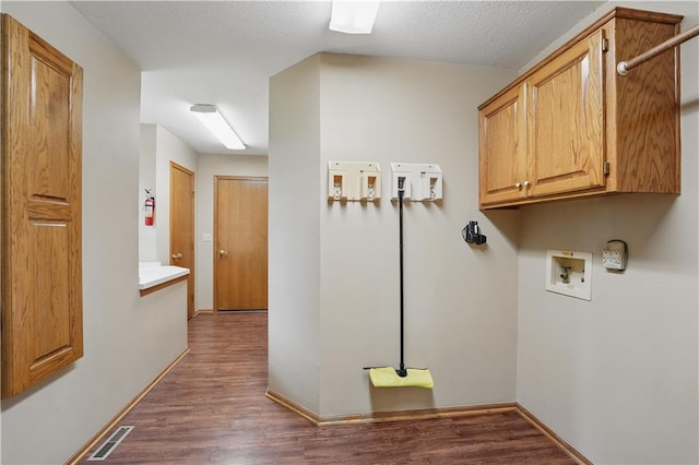 clothes washing area with cabinet space, washer hookup, baseboards, wood finished floors, and visible vents