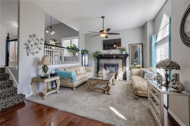 living room with wood finished floors, a ceiling fan, a glass covered fireplace, stairs, and baseboards