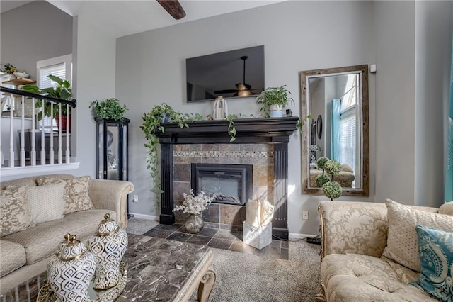 living room with ceiling fan, baseboards, and a tiled fireplace