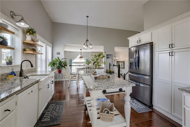 kitchen with stainless steel fridge, dishwasher, a sink, white cabinetry, and light stone counters
