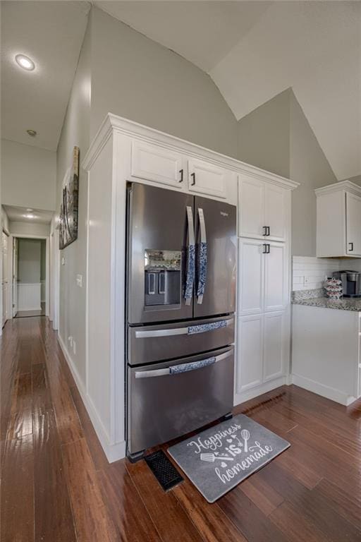 kitchen featuring stainless steel fridge with ice dispenser, dark wood finished floors, white cabinets, vaulted ceiling, and light stone counters