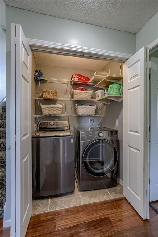 washroom featuring washing machine and dryer, wood finished floors, and a textured ceiling