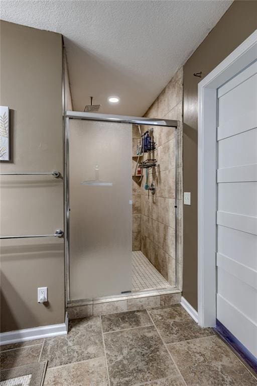 bathroom featuring a shower stall, baseboards, a textured ceiling, and recessed lighting