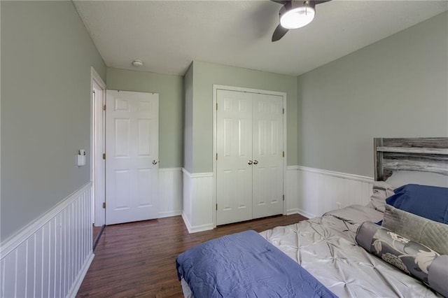 bedroom with wainscoting, wood finished floors, a closet, and ceiling fan