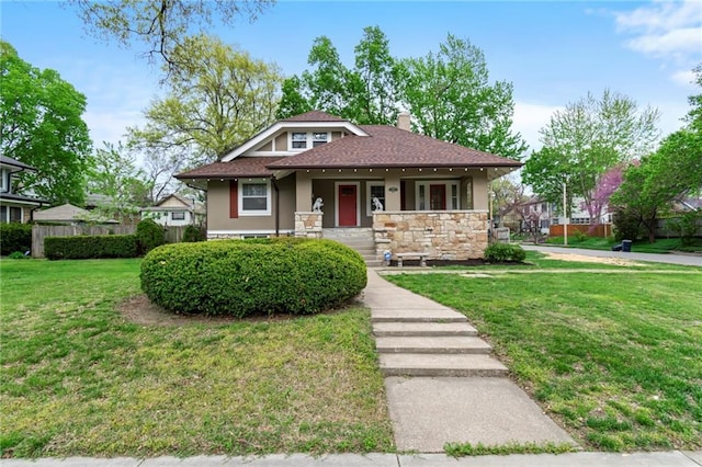 5547 Rockhill Rd, Kansas City, MO 64110 - bungalow-style home featuring a chimney, stone siding, covered porch, a front yard, and stucco siding