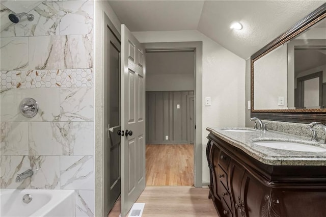 5547 Rockhill Rd, Kansas City, MO 64110 - full bath featuring vaulted ceiling, wood finished floors, a sink, and visible vents
