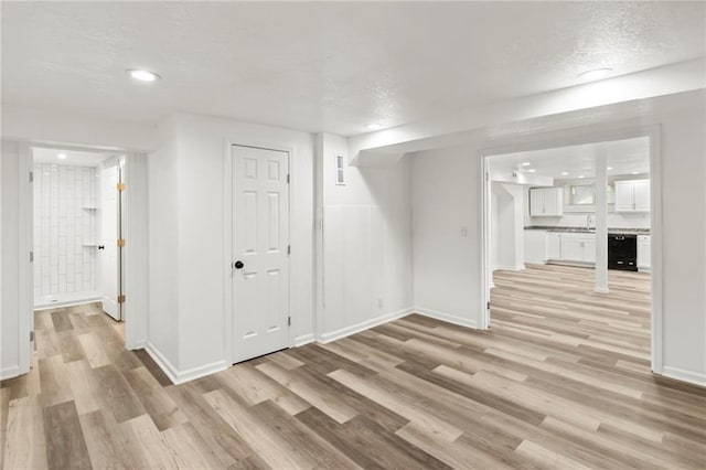 5547 Rockhill Rd, Kansas City, MO 64110 - unfurnished living room with light wood-style floors, a textured ceiling, baseboards, and wine cooler